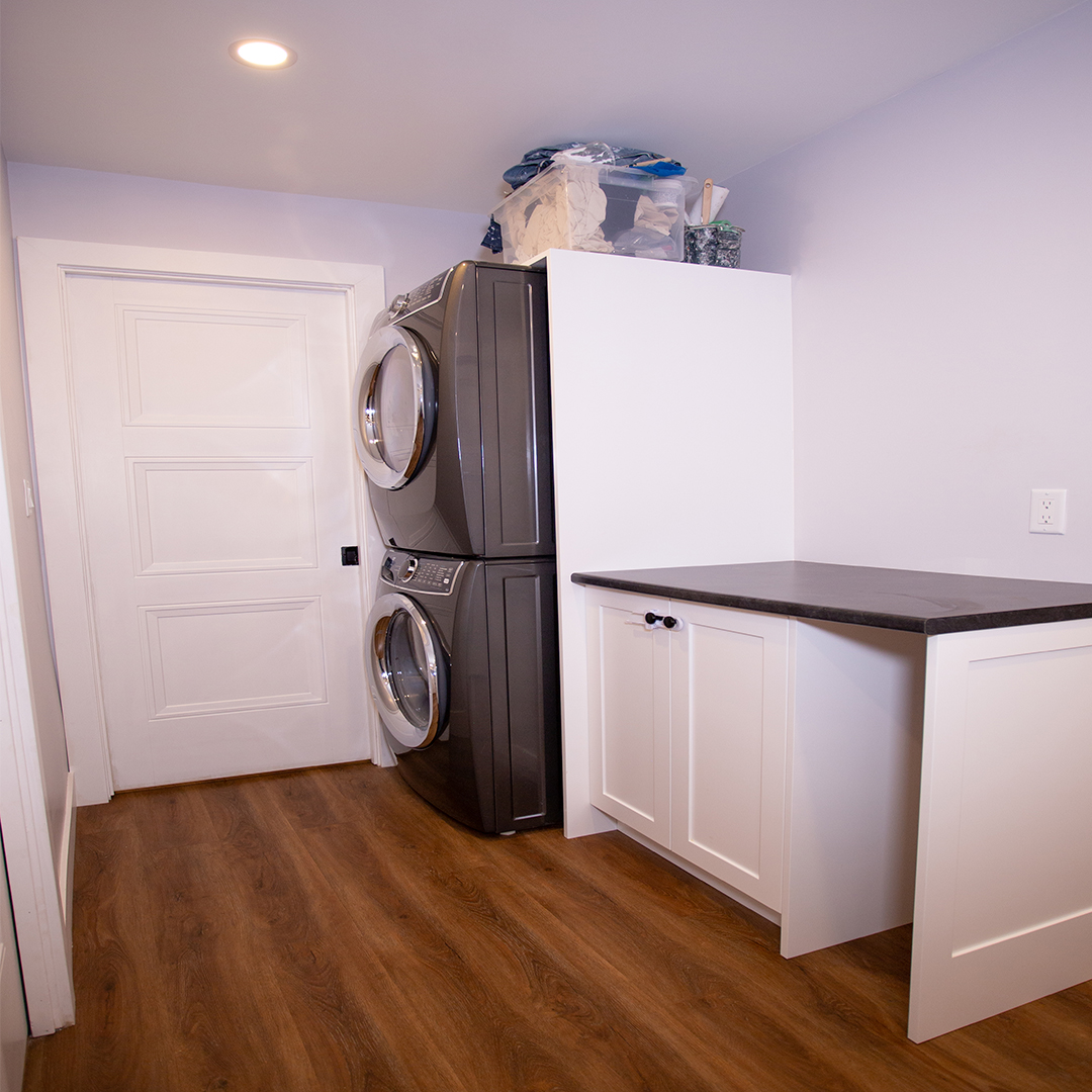 Stacking washer and dryer and laundry counter in modern basement hall