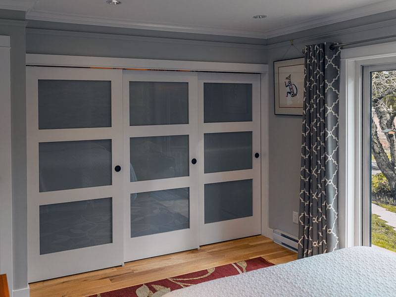 Closed triple sliding doors in bedroom with glass door to outside