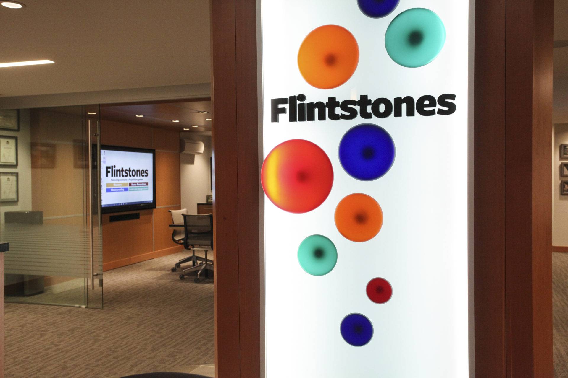 Office space with lit-up "Flintstones" sign and glass walls