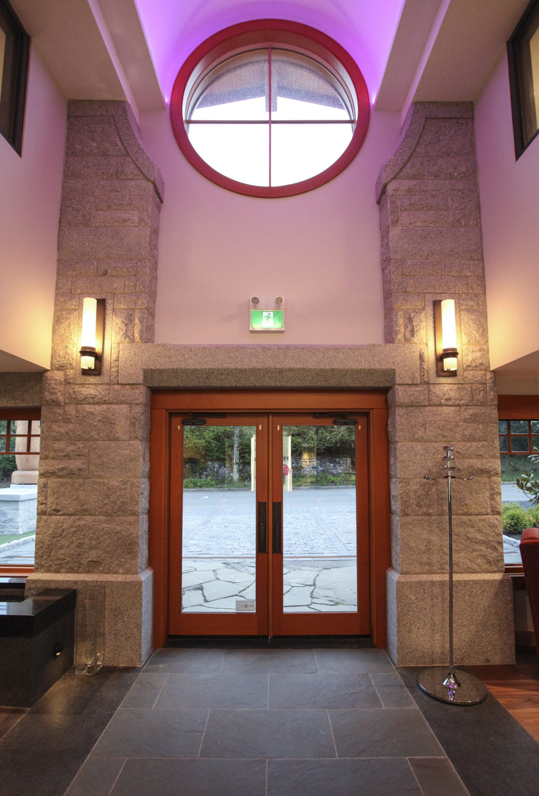 Double front doors with glass panels and a circular window in building looking outside