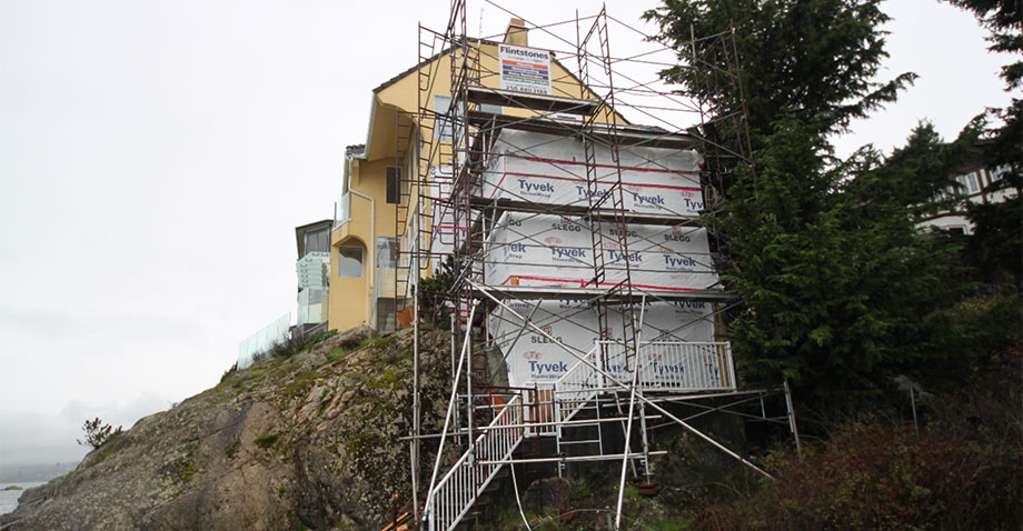 Scaffolding in front of yellow house on rocky sea shore