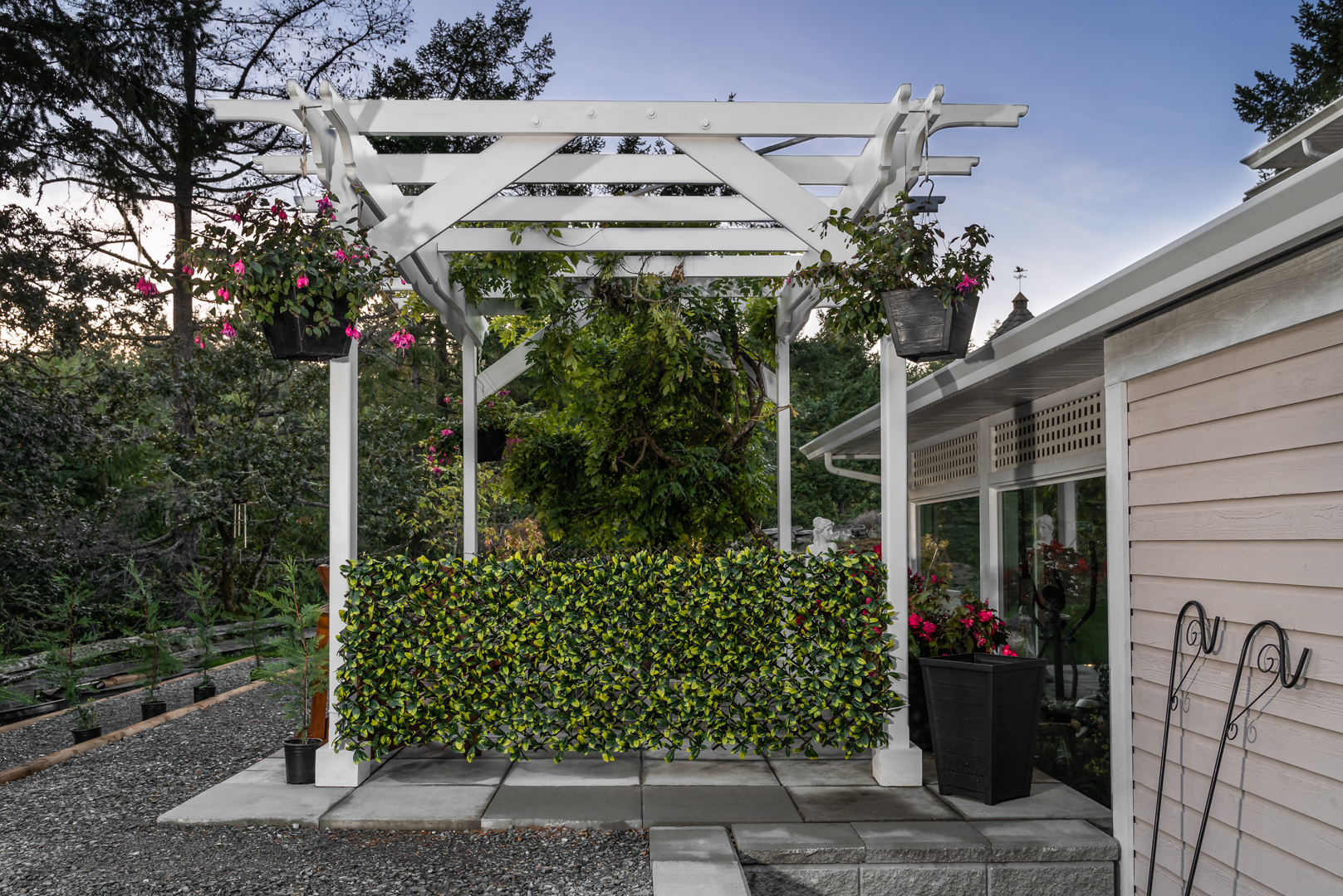 Pergola behind home with hanging plants