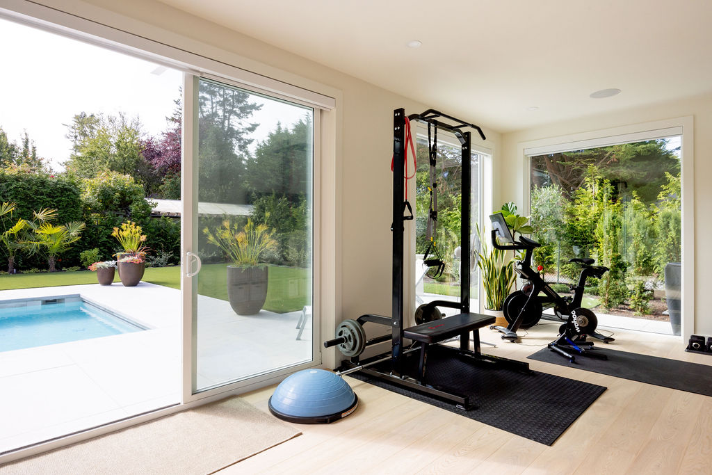 Home gym with exercise equipment and glass doors to outdoor pool area