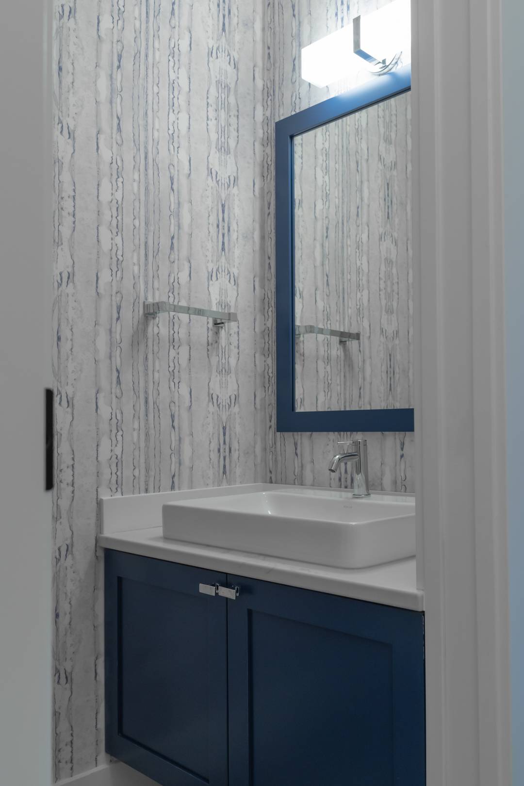 Modern bathroom with wallpaper and blue-framed mirror