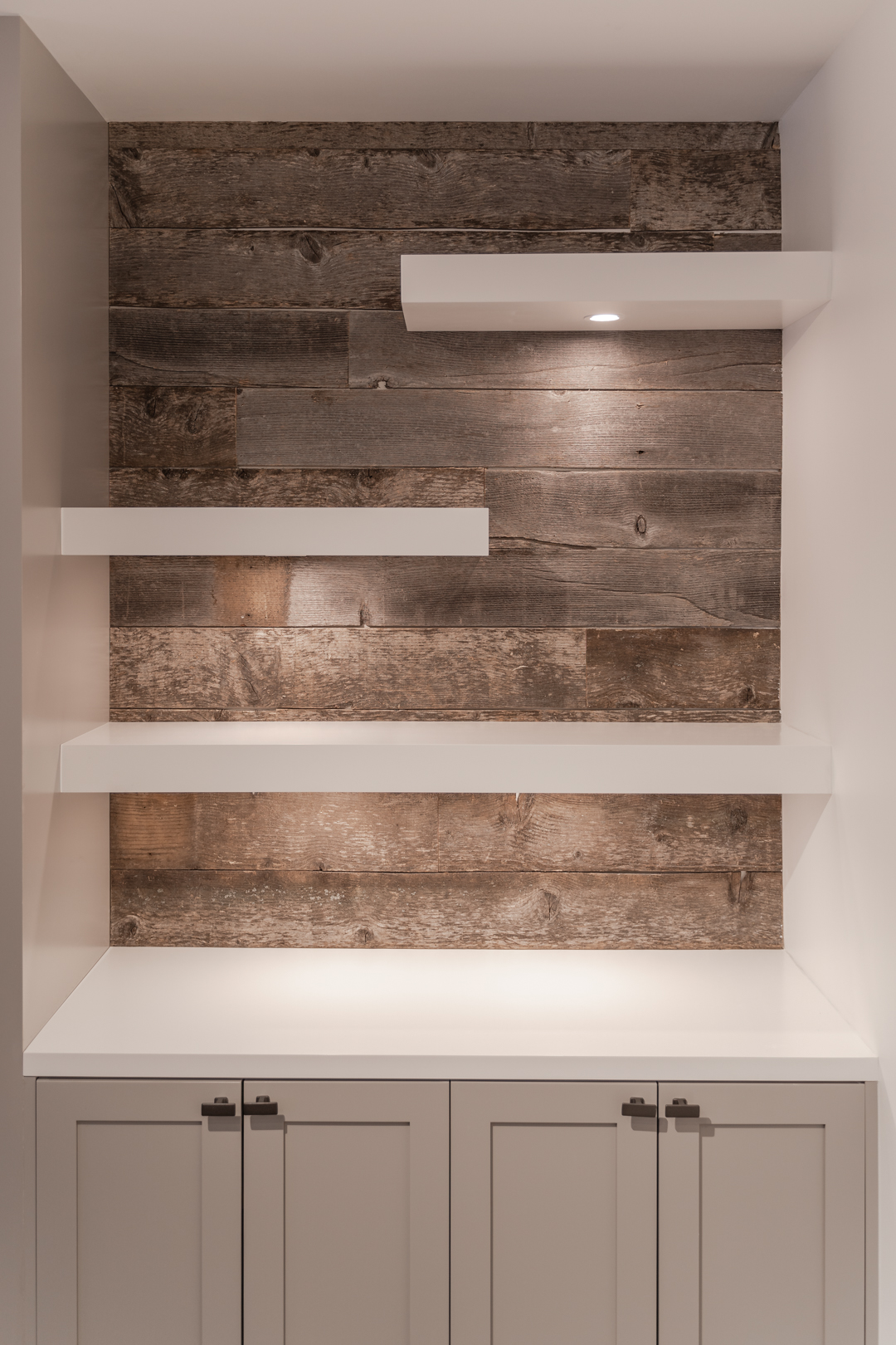 Built-in cabinets and white floating shelves with wood backing