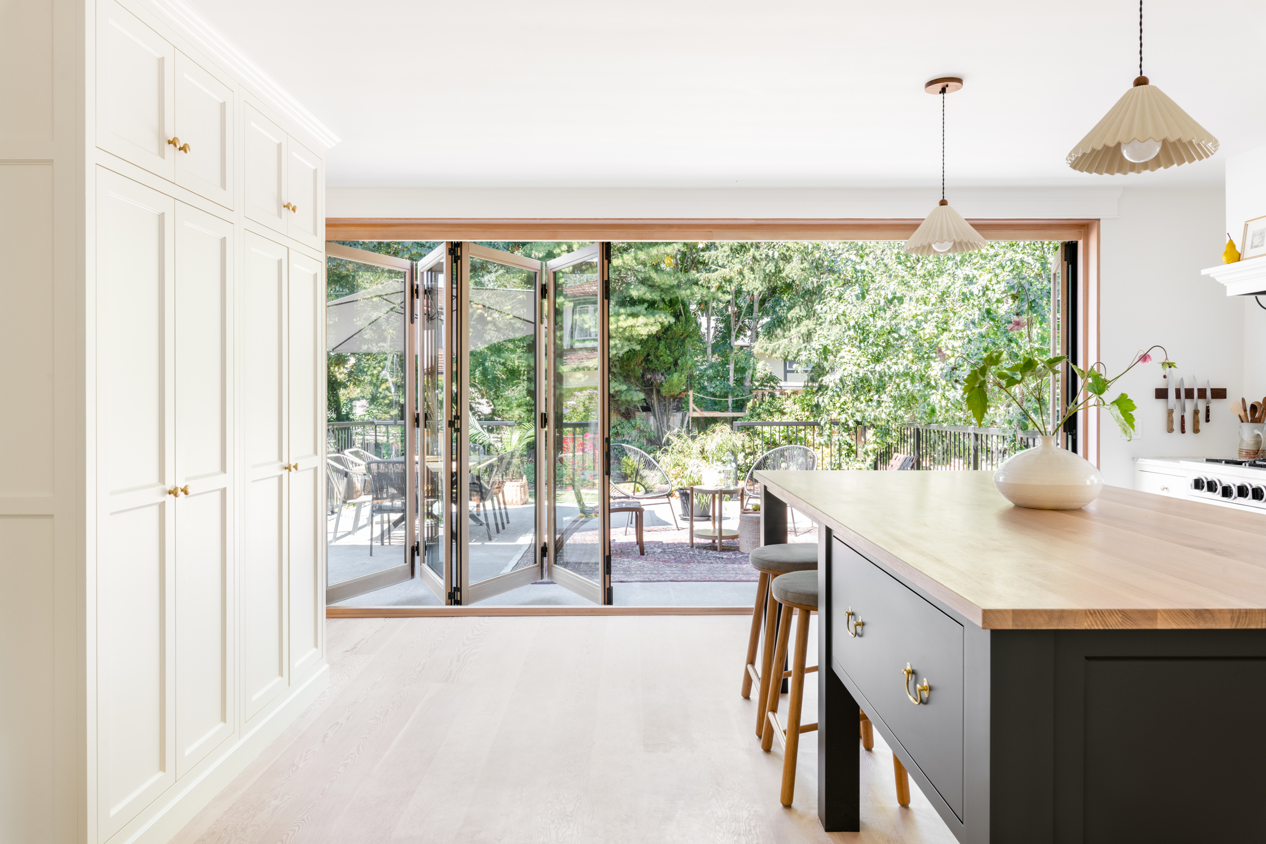 Kitchen of modern home opens onto patio with glass accordion door