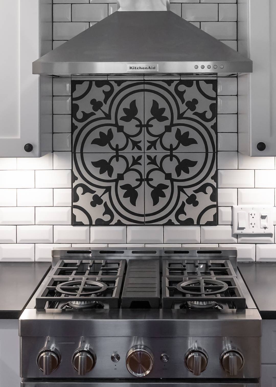 Modern kitchen with gas range, white tile backsplash, and black hardware