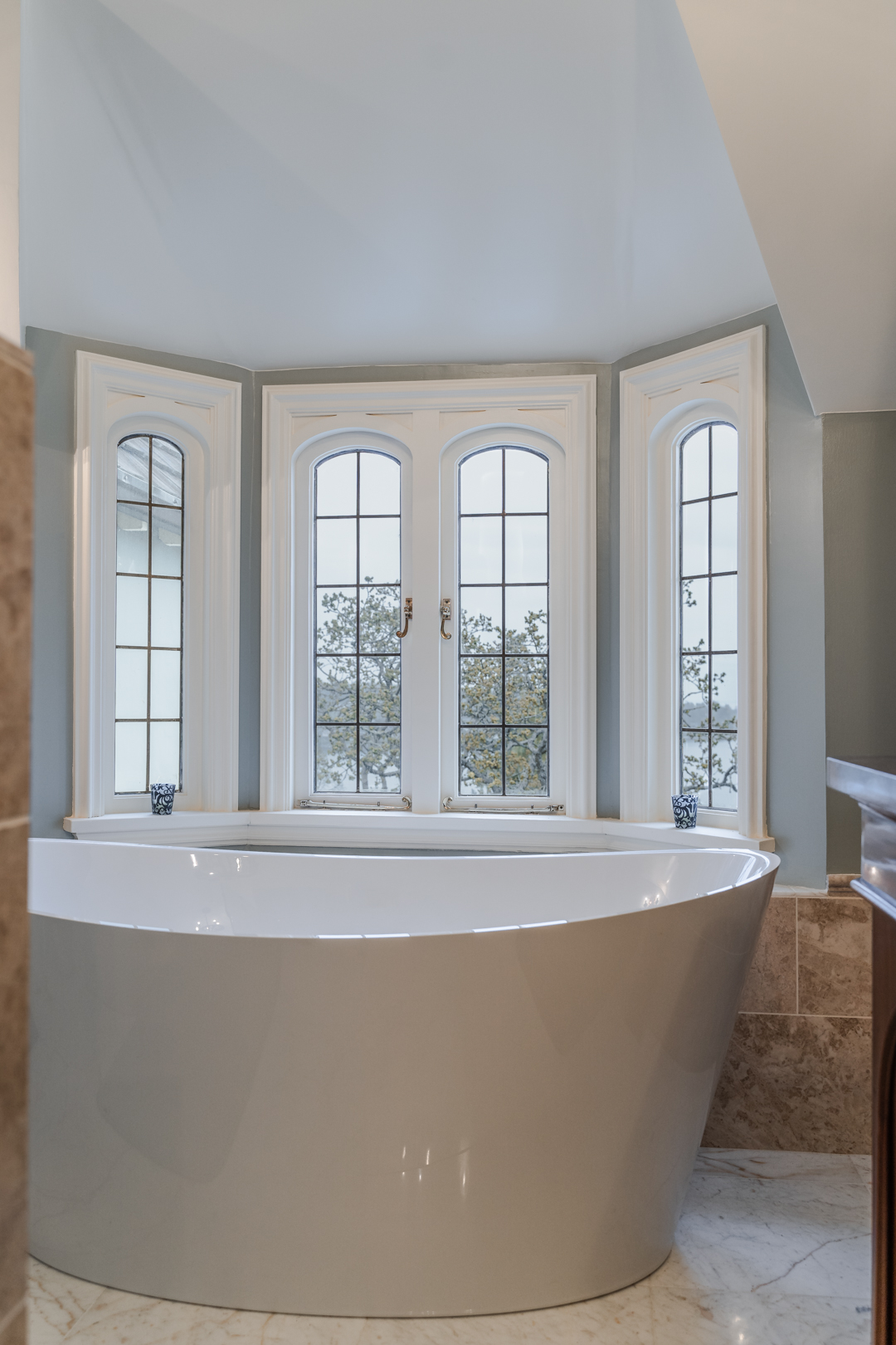 Freestanding bathtub surrounded by arched windows