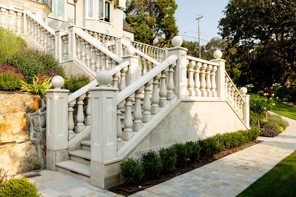 Multi-level staircase with concrete banister and well-manicured lawn and garden