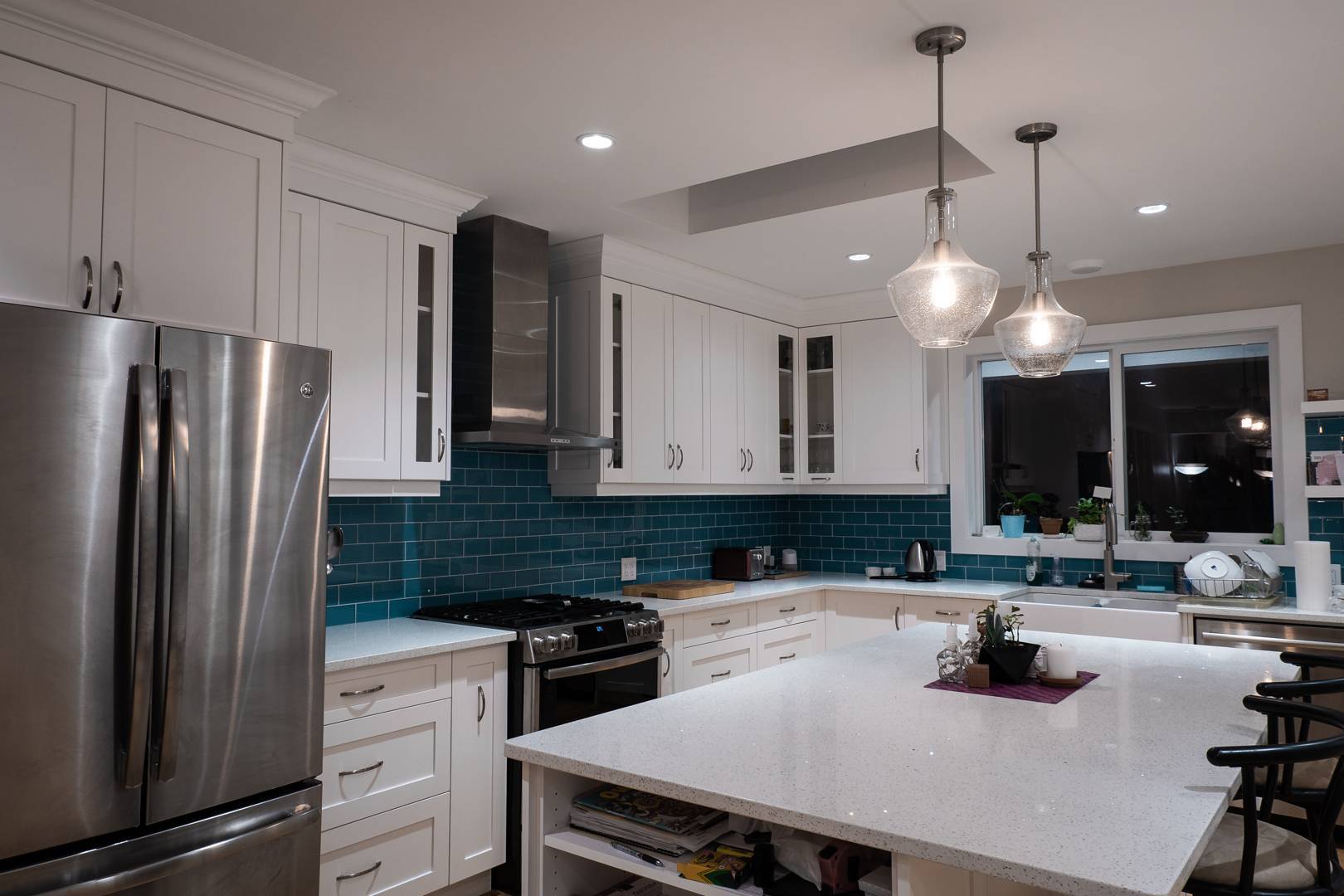 Modern kitchen with white cabinets, island, and teal blue tile backsplash