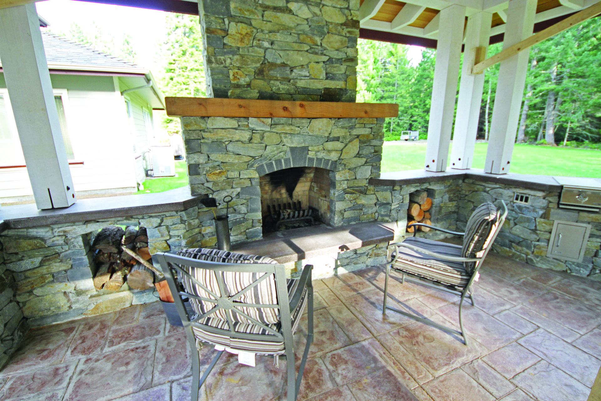 Stone and wood pavilion in backyard with fireplace